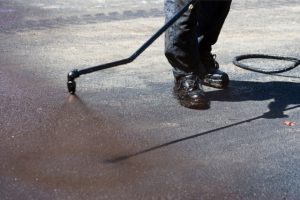 Worker spraying hot asphalt